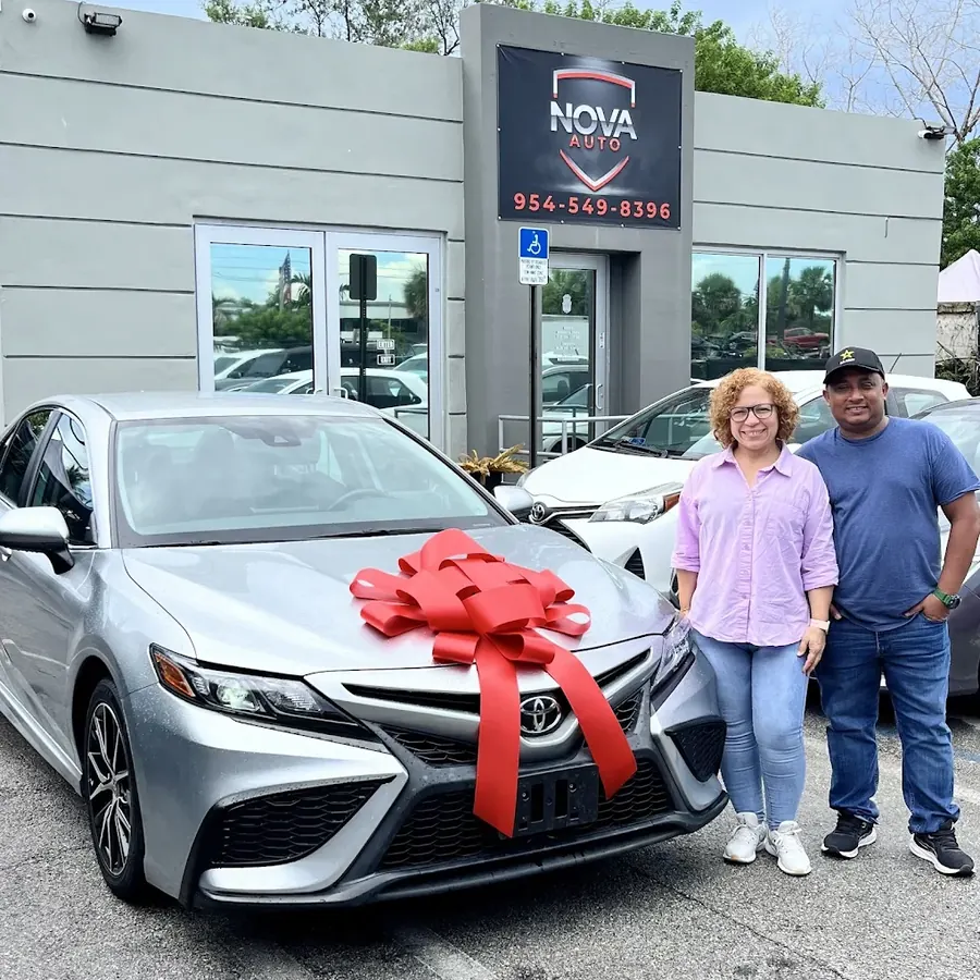 Pareja feliz recibiendo su Toyota Camry en Nova Auto
